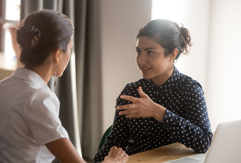 Two women making eye contact while talking with each other.