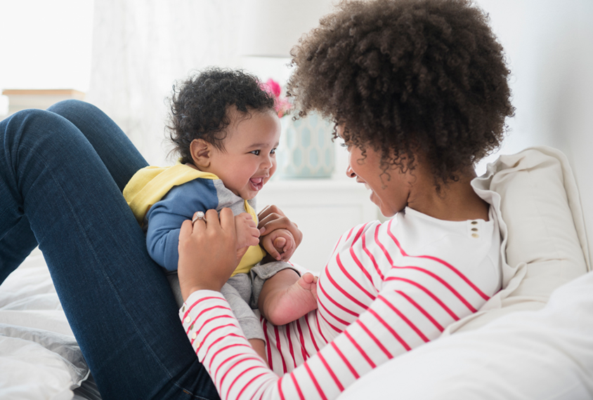 Baby in mother's lap watching her mouth move as she talks.