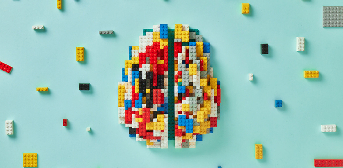 Brain composed of legos with various legos scattered around it.