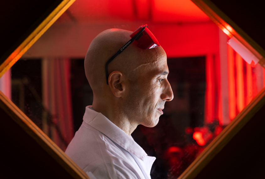 Ofer Yizhar in his lab, framed by rectangular window and a red background.