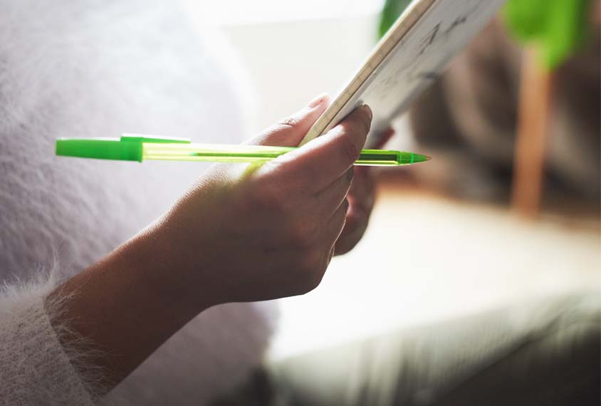 Person with documents and a green pen.