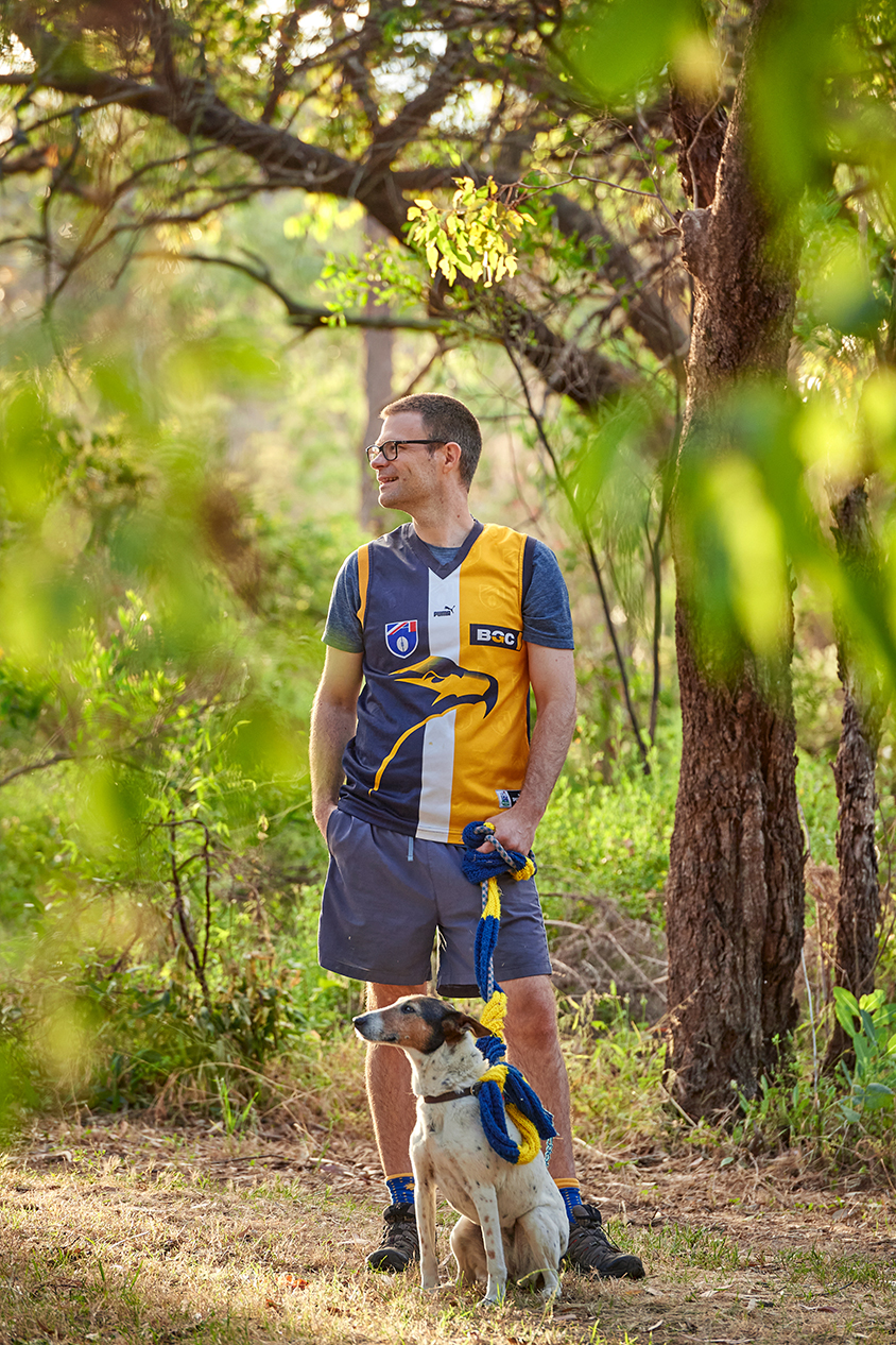 he Aussie Rules fanatic, Professor Andrew Whitehouse, walking his dog Abbie in the Australian bush--both wearing team regalia.