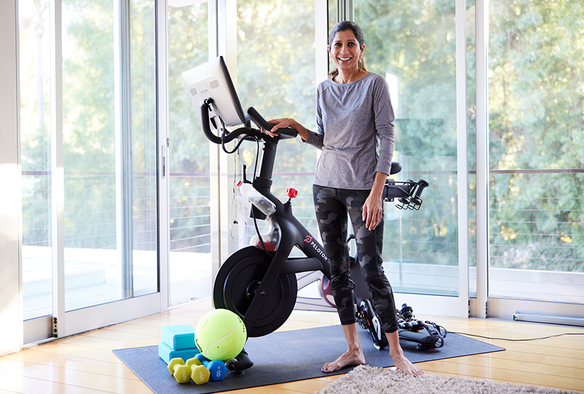 Dr. Jeste standing in her home gym, next to her Peloton machine. 