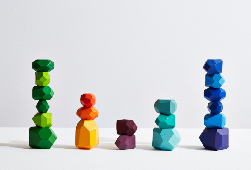 wooden pebble shapes stacked on top of each other, at varying heights, and according to colors of the spectrum.