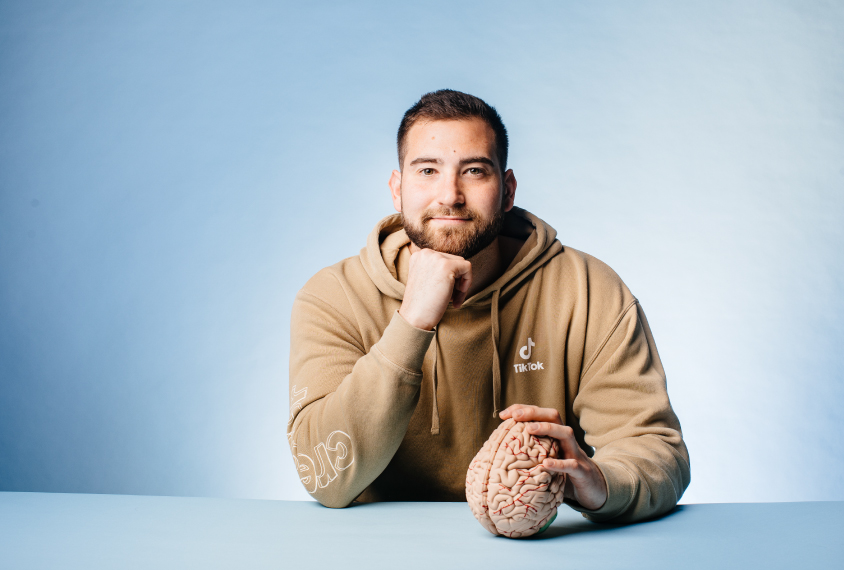 Dr. Ben Rein on light blue backdrop with a brain model. 