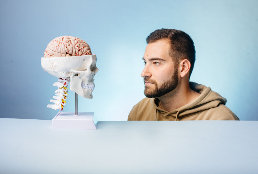 Dr. Ben Rein on light blue backdrop with a skull and brain model. 