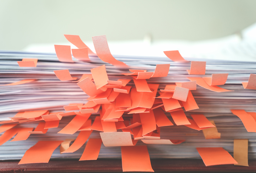 Stack of documents marked with red sticky notes.
