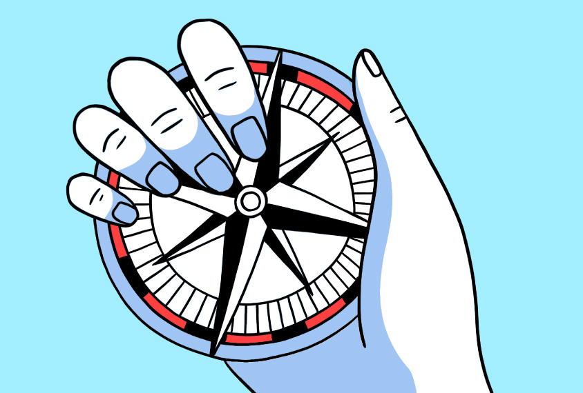 A hand holds a compass against a blue background.