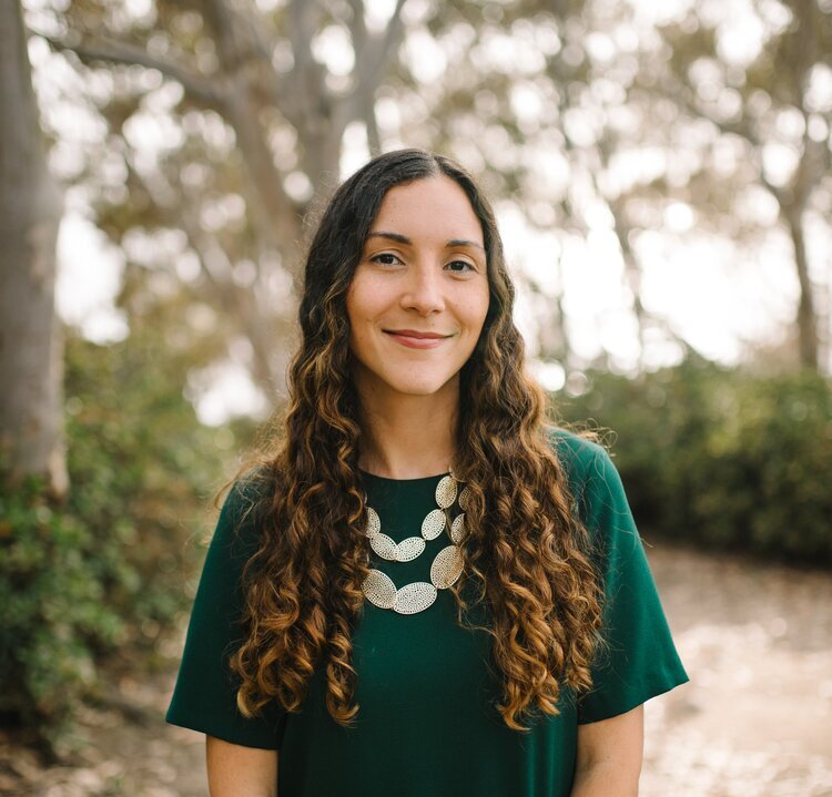 Headshot of Nancy Padilla-Coreano. She is standing outdoors wearing a green shirt and giving a soft smile.