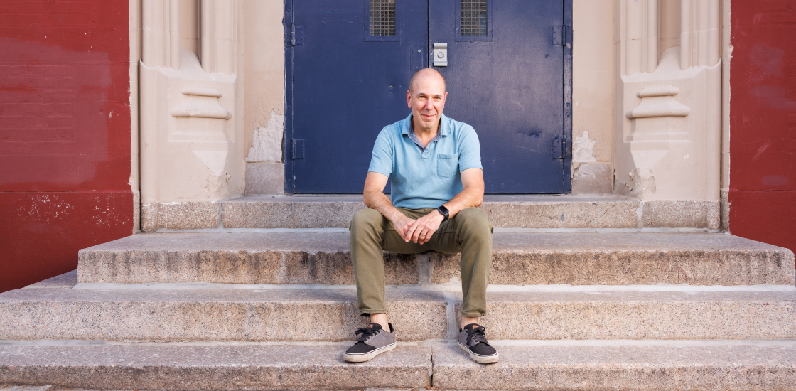 David Mandell sits on the steps of a school.