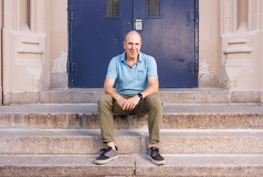 David Mandell sits on the steps of a school.