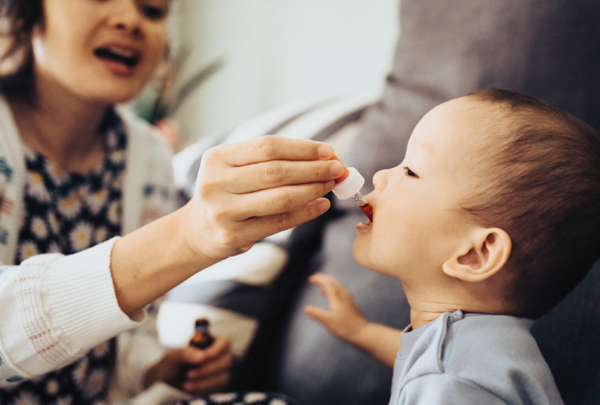 An adult administers a medication to an infant.