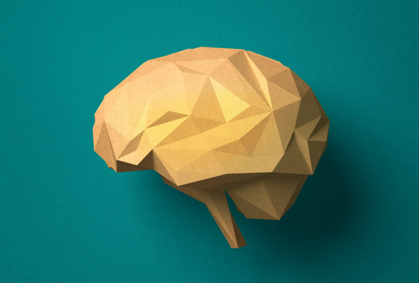 A brown brain model made of paper set against a dark green background.