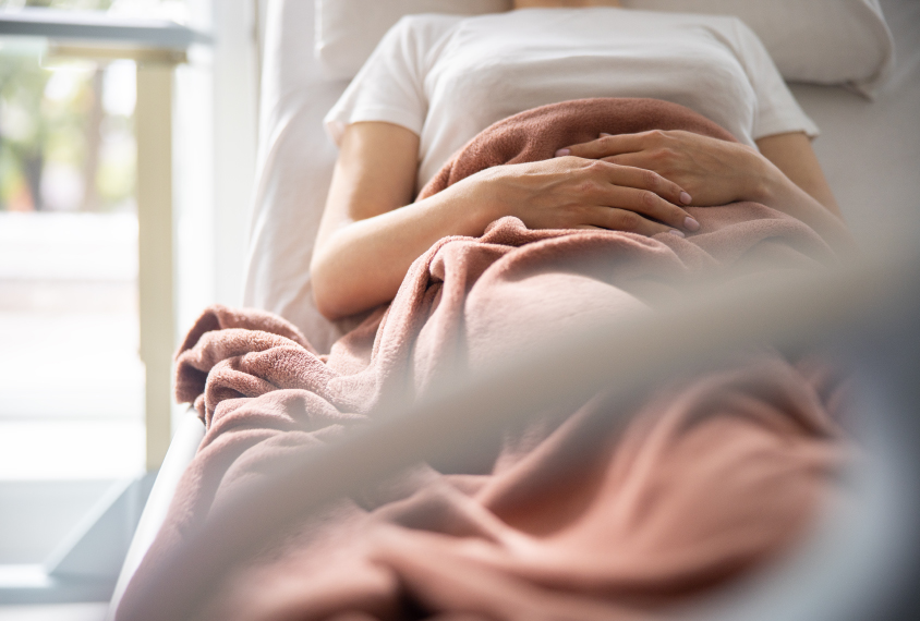 A pregnant woman lies in a hospital bed.