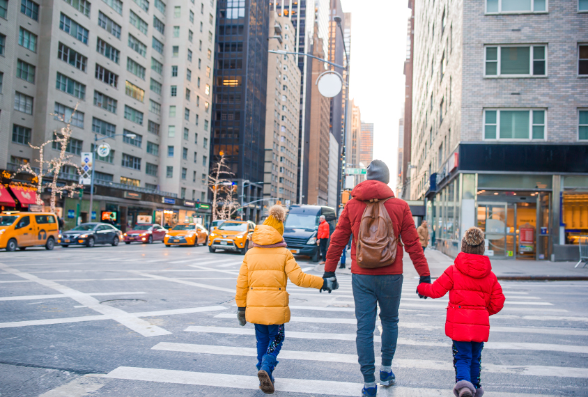 Photograph of a parent crossing a city street with two children