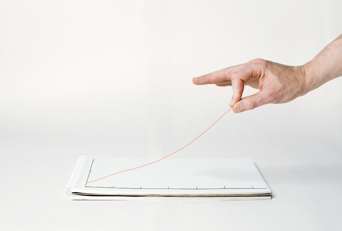 A hand lifts a line graph off of a page and into the air.