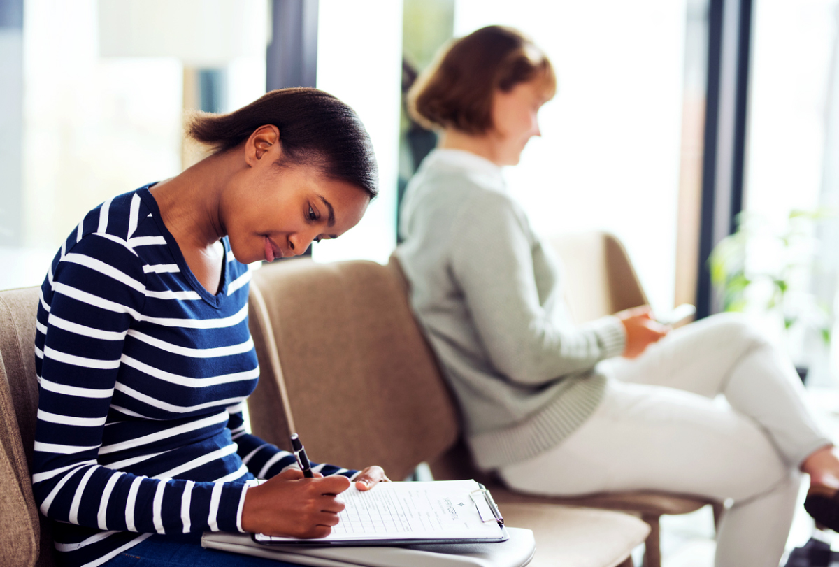 A patient fills out a form in a doctor's office waiting room