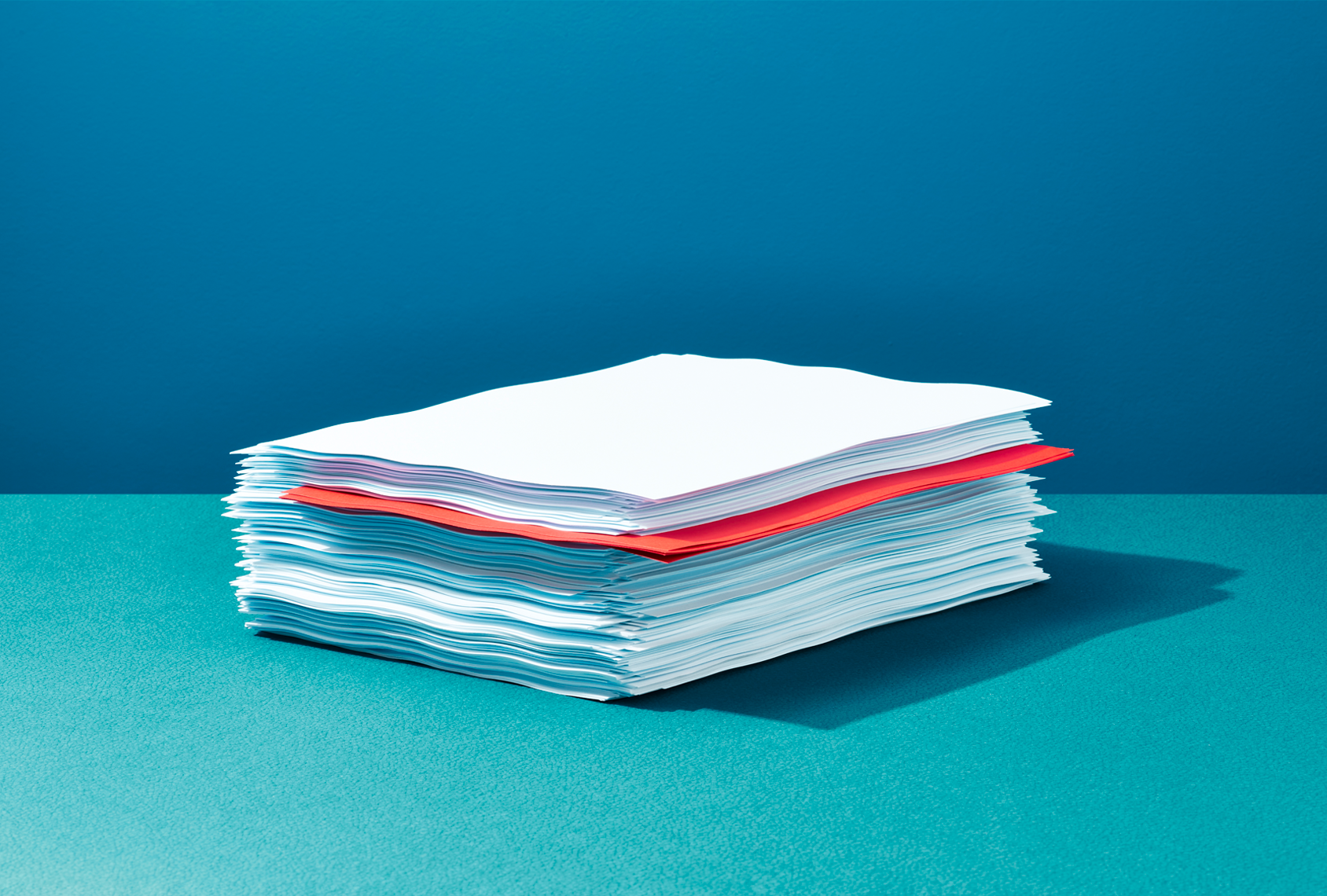 A stack of papers sits on a blue table.