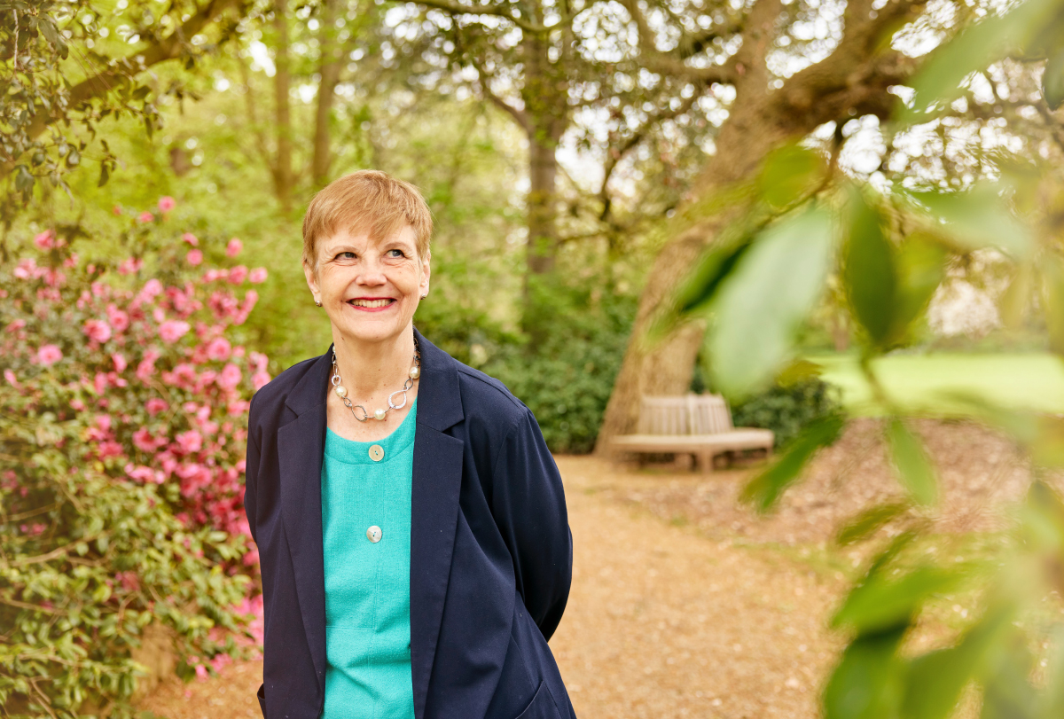 Photograph of Dorothy Bishop standing in an outdoor garden and smiling.