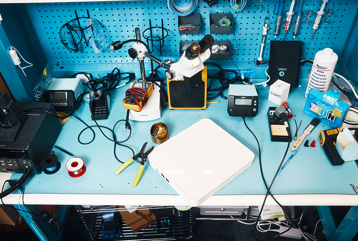 The Emerald sleep tracker, a white box, sits on a blue workbench surrounded by electronic equipment.