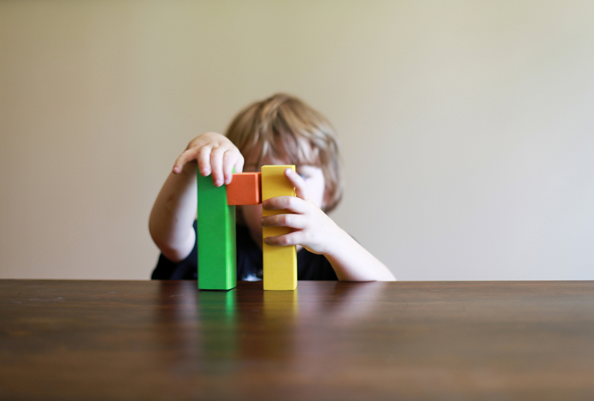 Young child stacks colored blocks on a table.