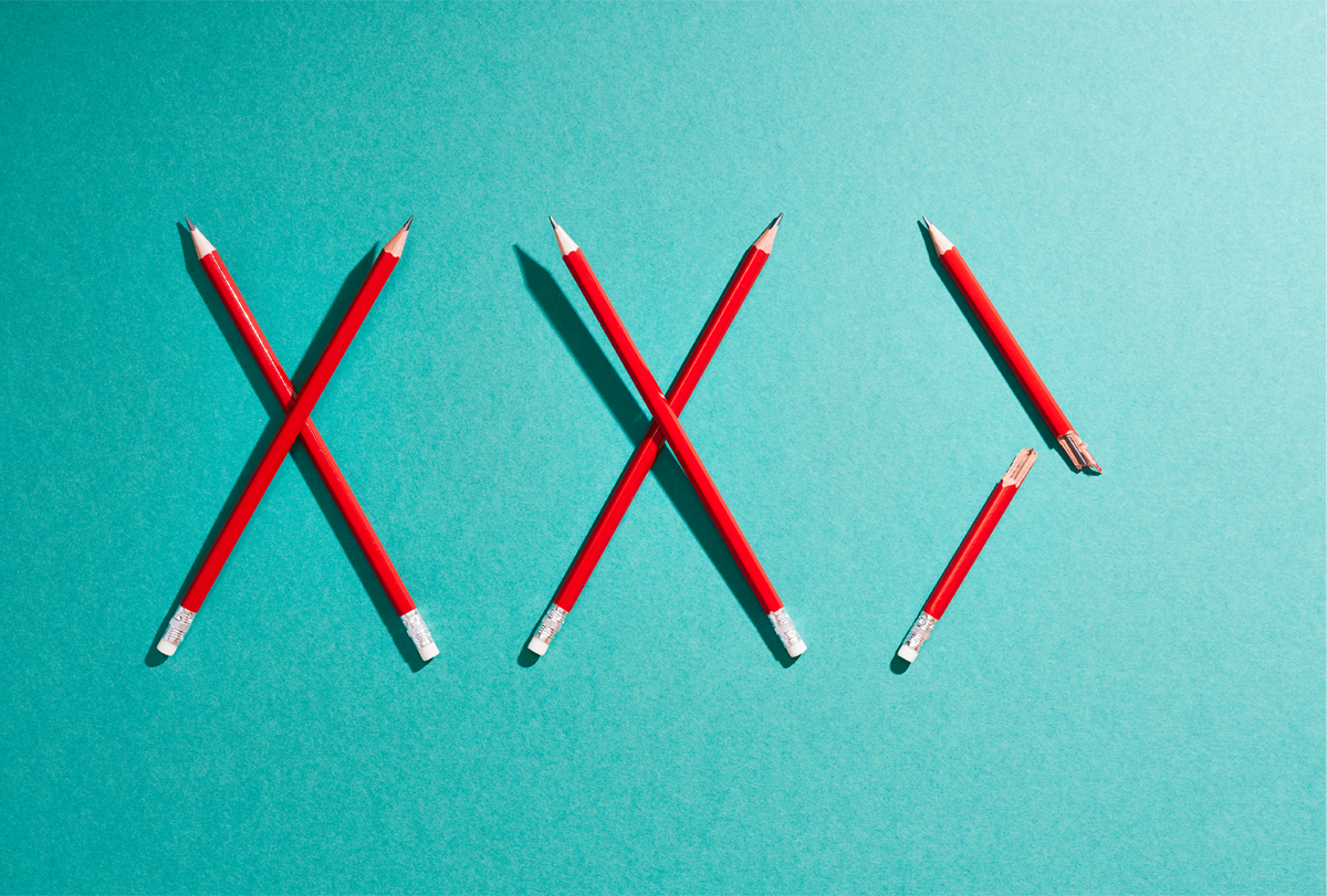 A series of red pencils make three X shapes against a green background. The last X is only half completed by a single pencil that has been snapped in two.