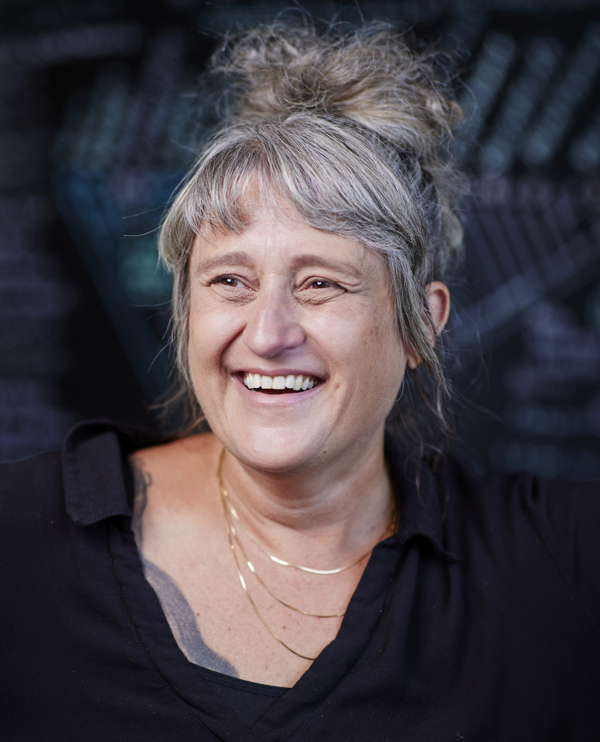 Scientist Gül Dölen smiling in her office, dark chalkboard in background.