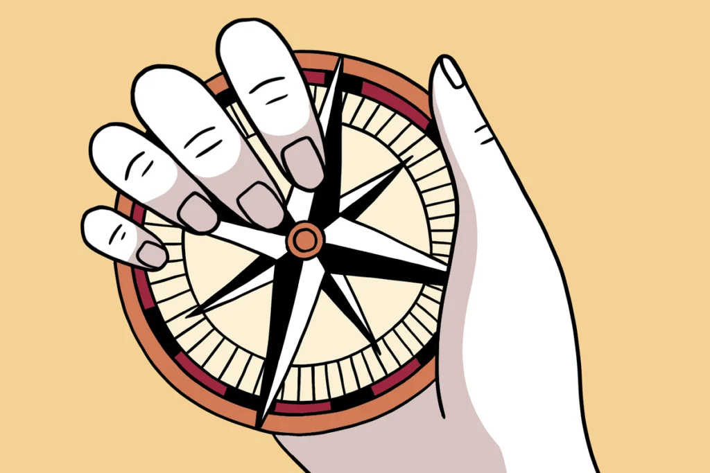 A hand holds a compass against a light orange background.
