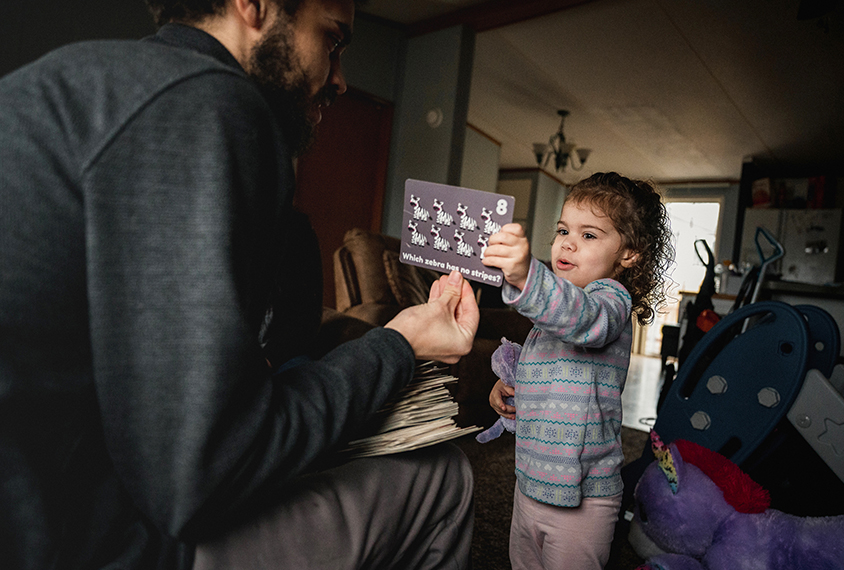 Coraline’s father holds out an educational picture card for Hannah.