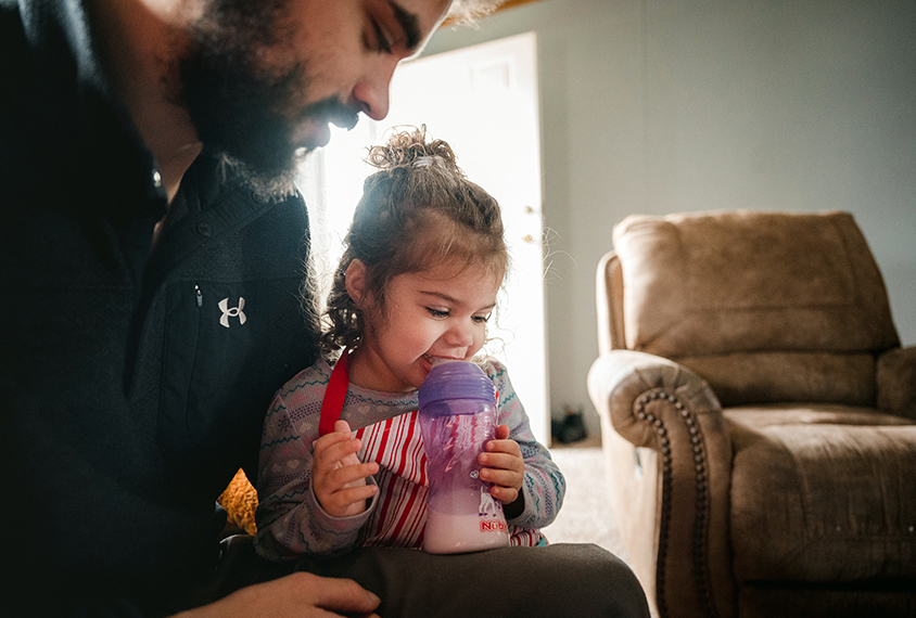 Coraline sits with her father in their home.