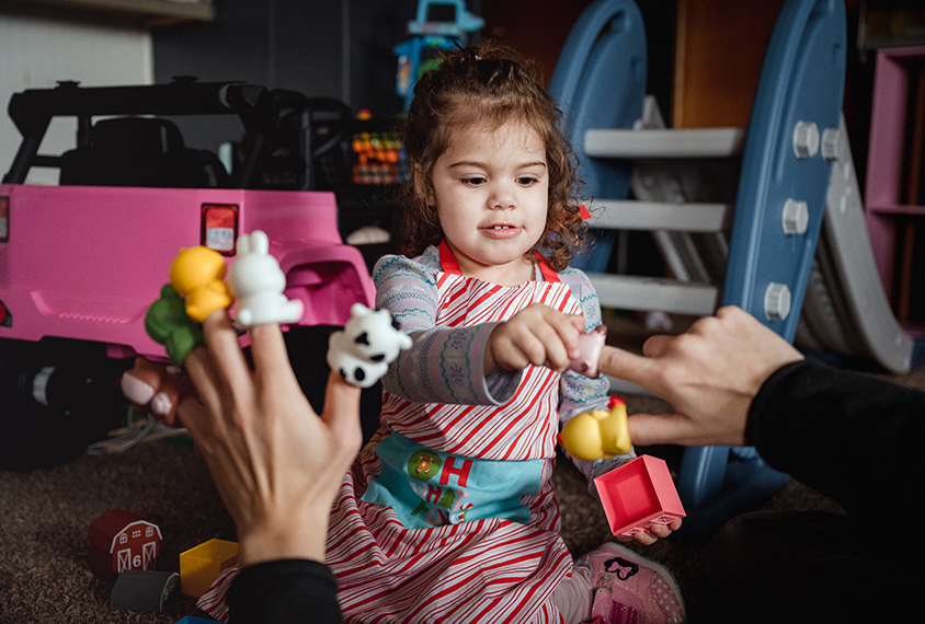 Coraline points to a finger puppet on her father's hand.