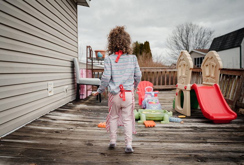 Coraline walks on her tip toes outside in a play area at her home.