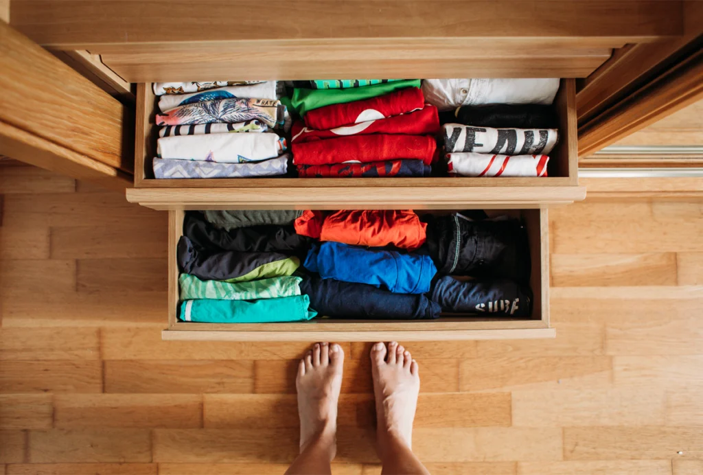 A person stands in front of a neatly organized dresser drawer.
