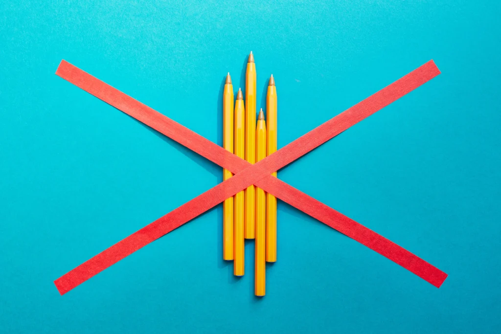 A photograph of pencils with a red X over them
