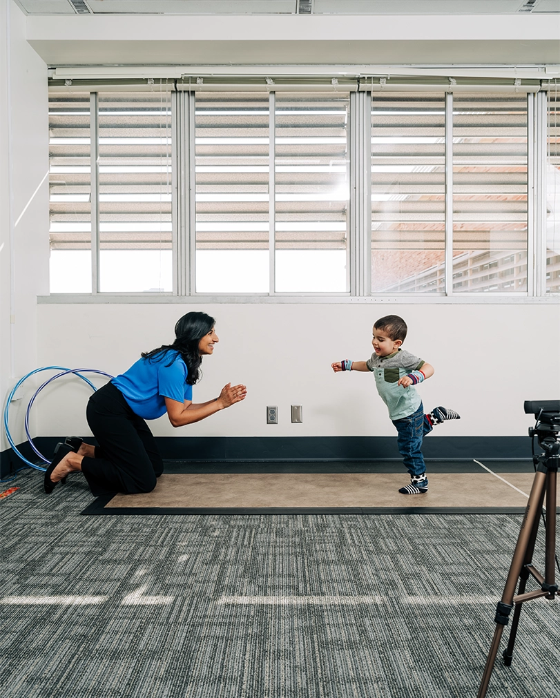Rujuta Wilson and a toddler on the gait mat in her lab.