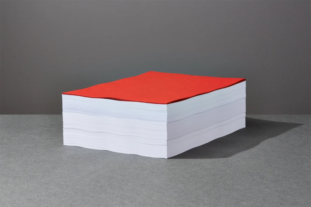 A stack of papers with a red paper on top.