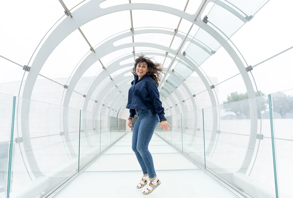 Photograph of Eugenia Chiappe jumping inside a glass hallway.