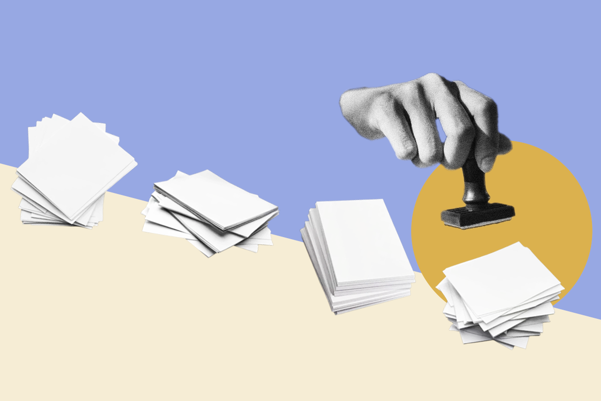 A disembodied hand holds a stamp over a messy stack of papers.