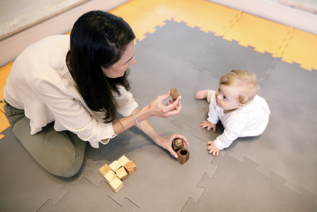 A woman plays with a child on the floor.
