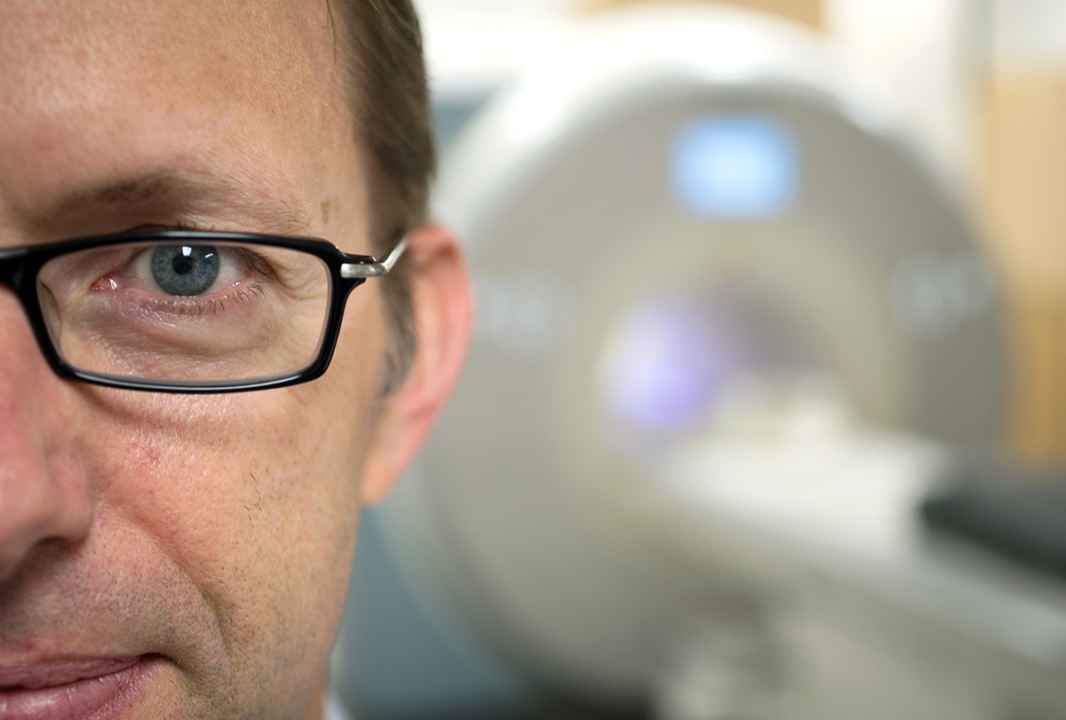 Researcher Russell Poldrack's face closeup, with a scanner seen out of focus behind him.