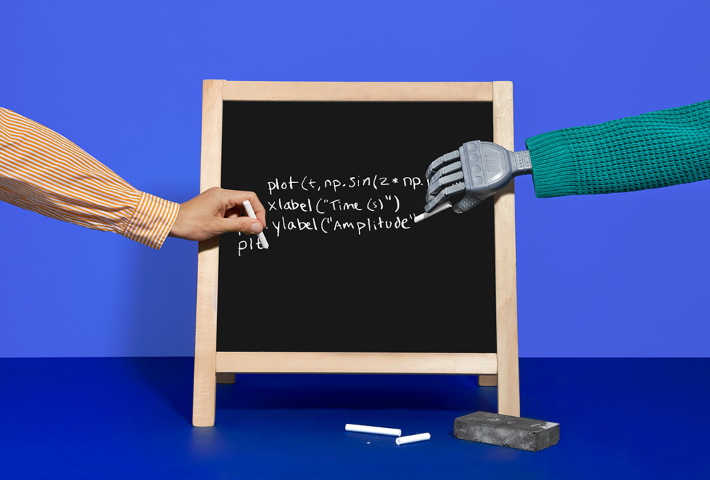 A human arm and a robot arm write code together on a small blackboard.