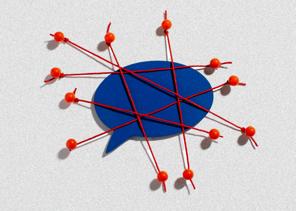 A blue comment bubble is pinned down by crisscrossing red threads and pins.