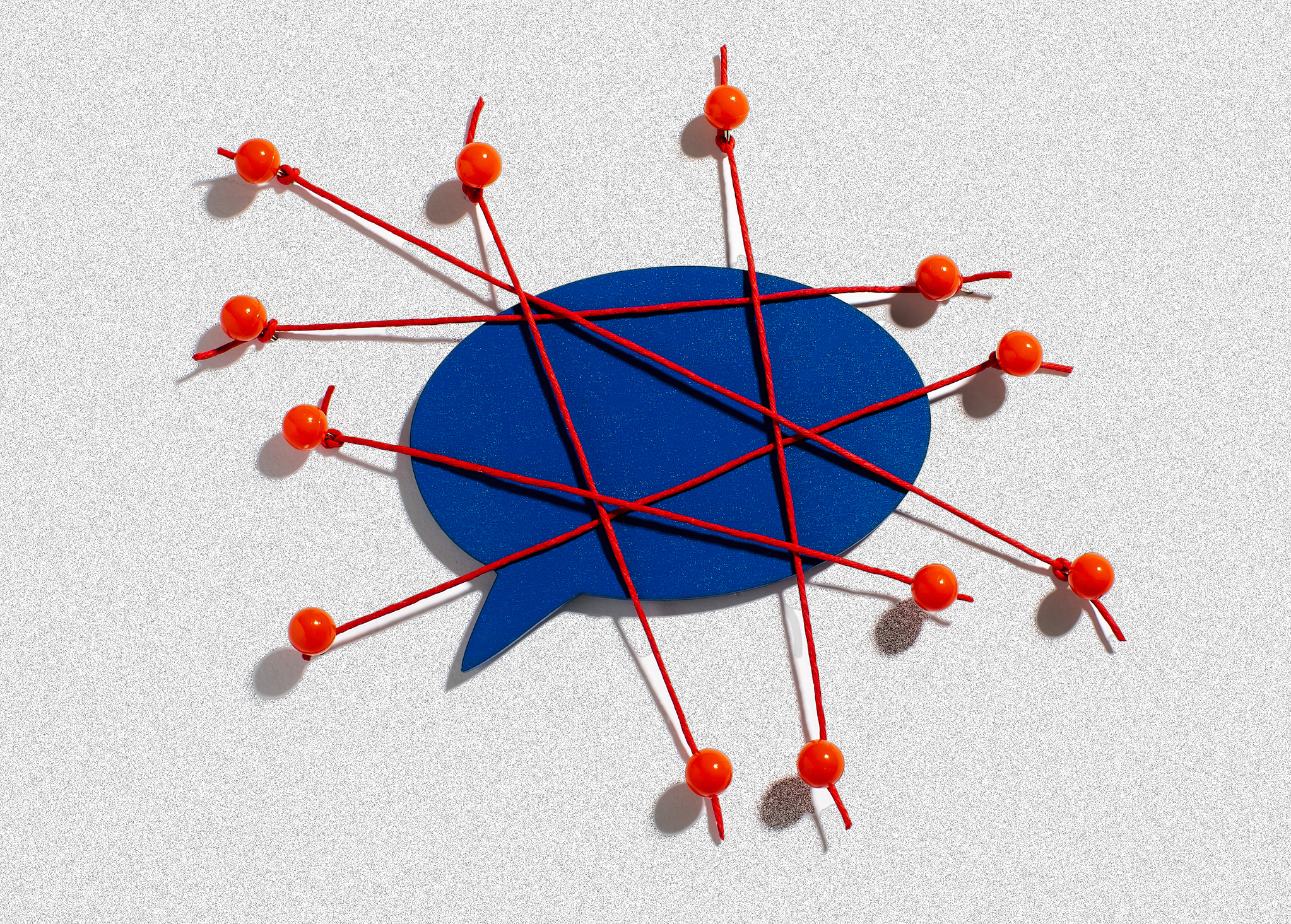 A blue comment bubble is pinned down by crisscrossing red threads and pins.