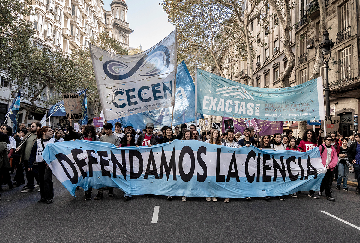 Los manifestantes marchan por la calle portando una pancarta que dice "Defendamos la ciencia".