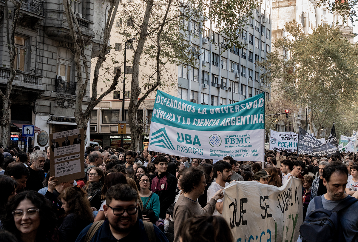 Manifestantes portan pancartas y corean consignas en las calles de Buenos Aires: una multitud que lleva grandes pancartas llena las calles, y a un lado se divisan edificios.
