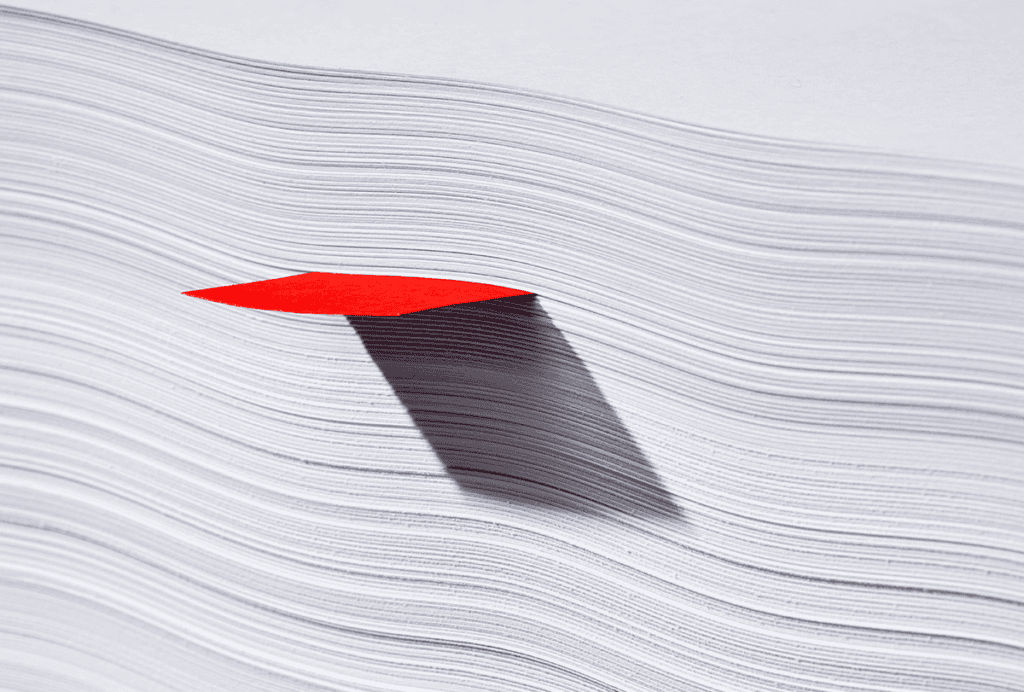 Red note stuck in a stack of paper.