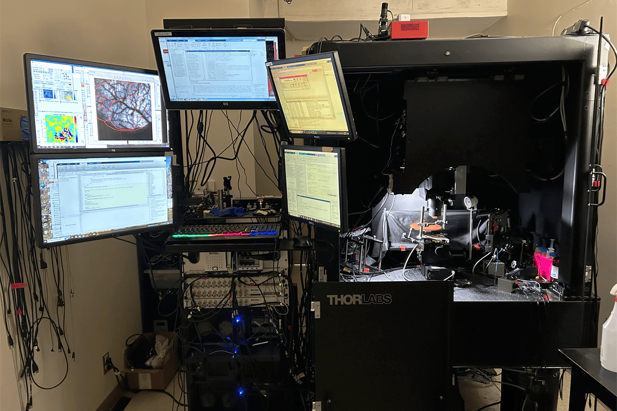 Front view of holographic mesoscope rig with multiple monitors inside a lab.